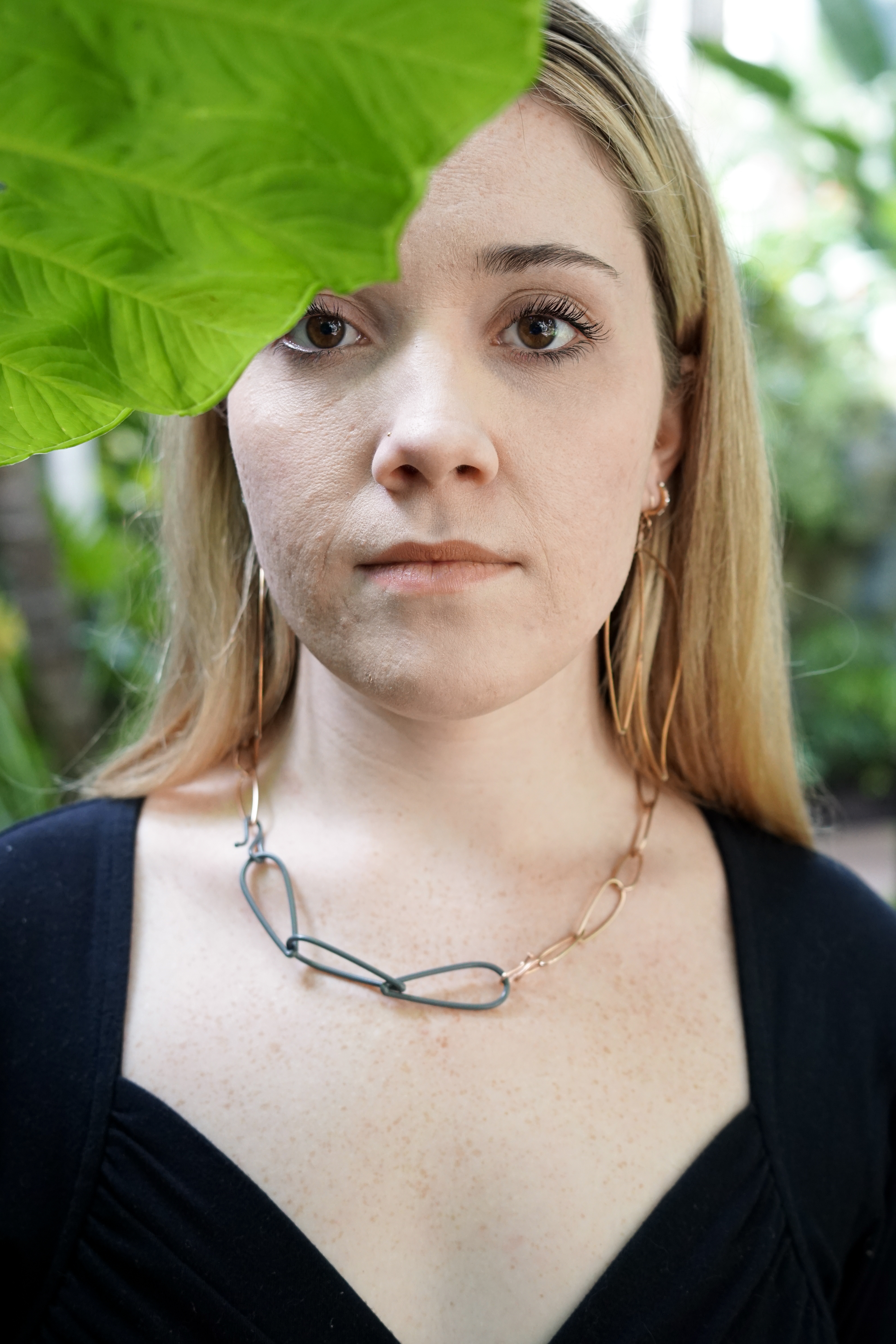 Trista wearing bronze and grey necklace and bronze statement earrings with large green leaf