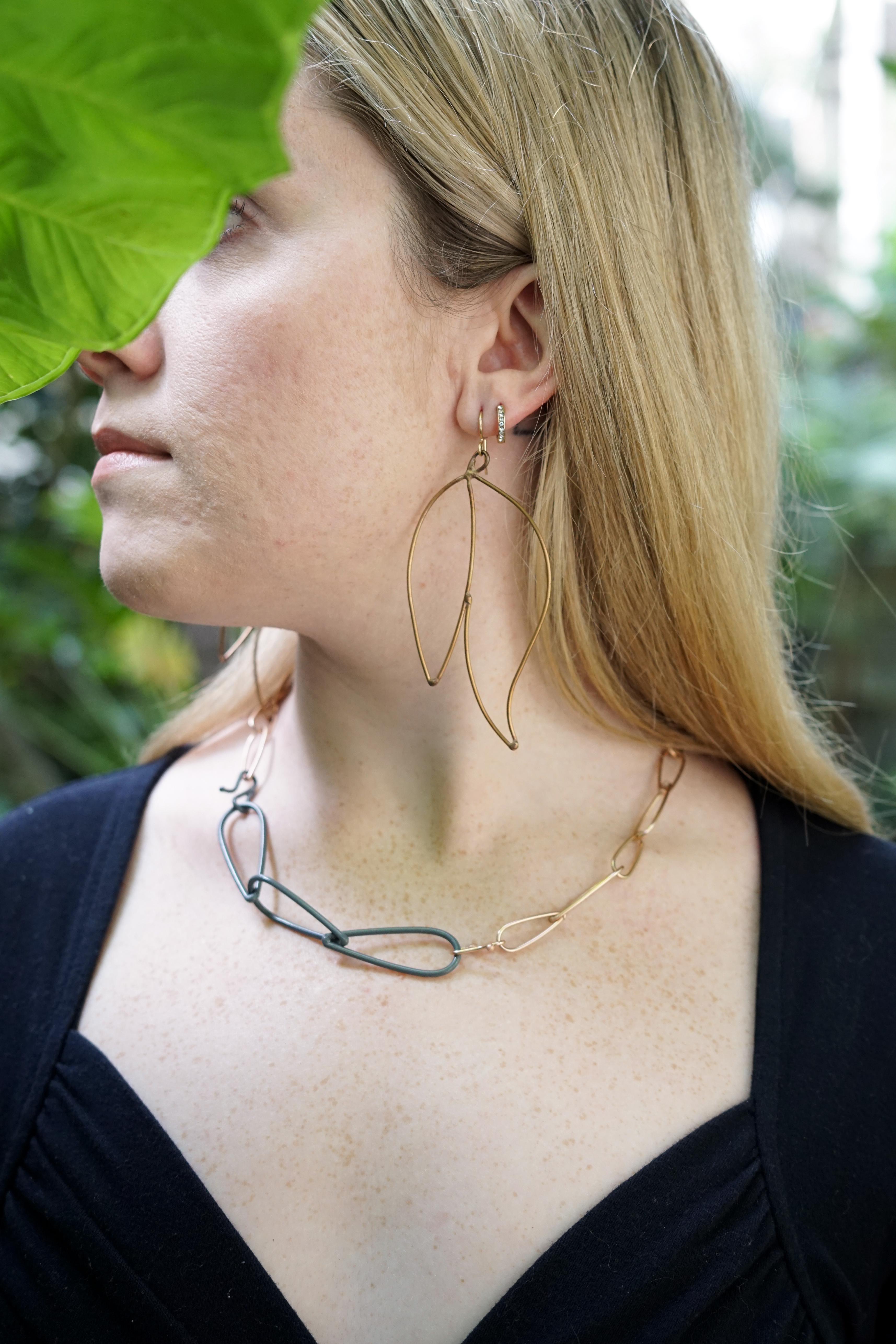 Trista wearing bronze and grey necklace and bronze statement earrings with large green leaf