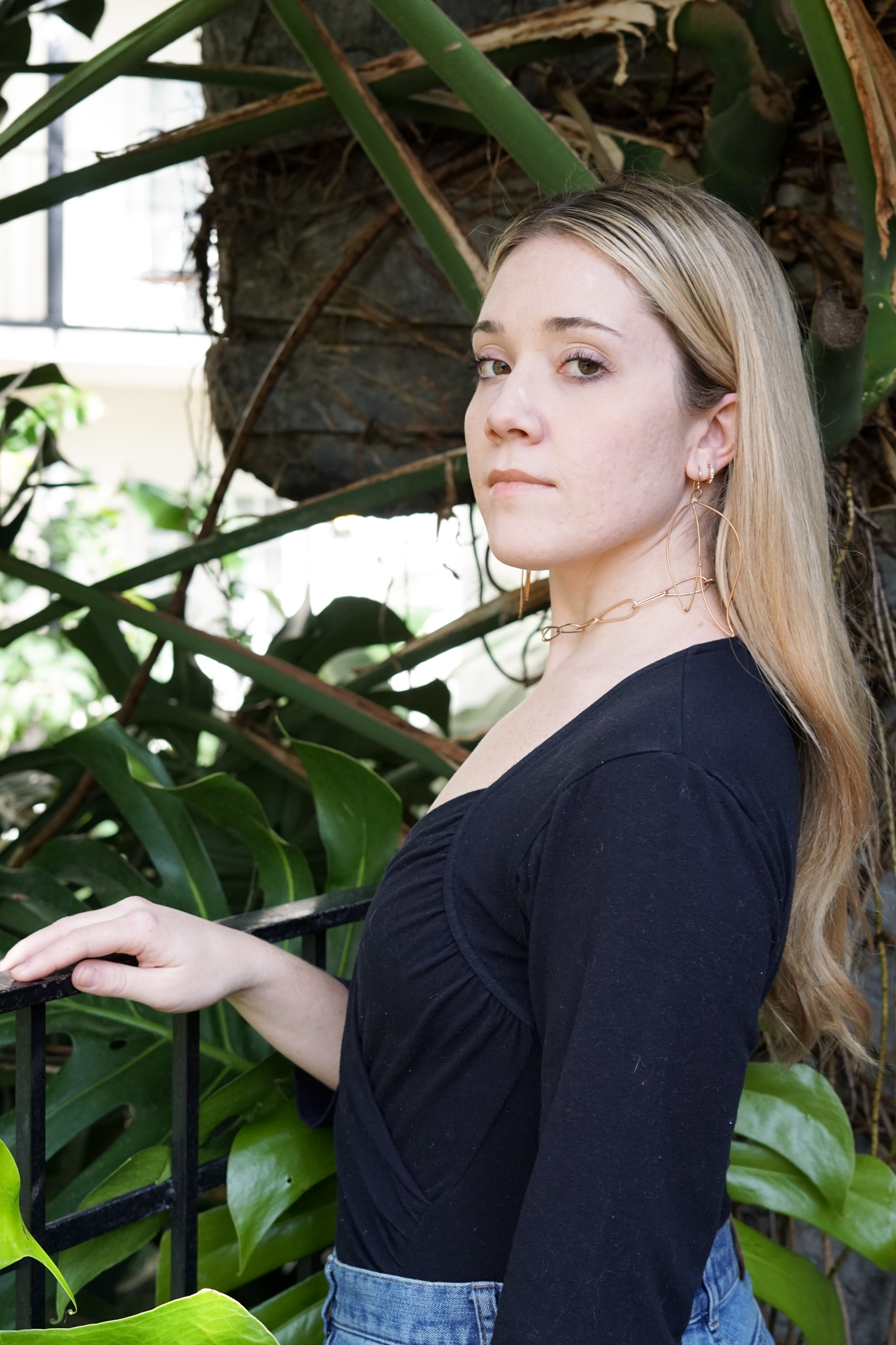 Trista in the garden wearing bronze statement earrings and bronze chain link necklace