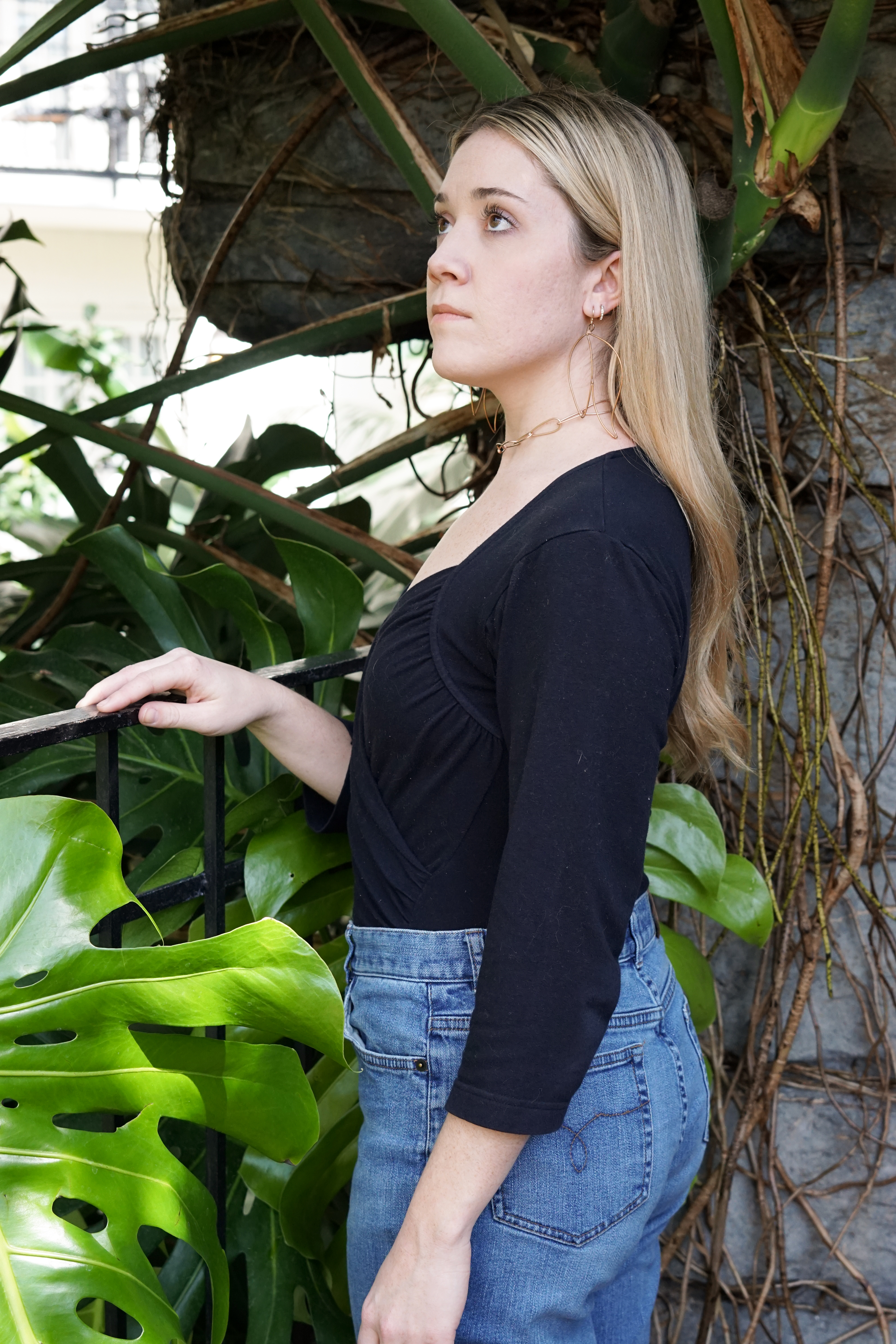 Trista in the garden wearing bronze statement earrings and bronze chain link necklace
