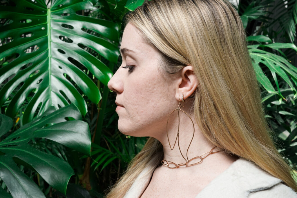 Trista with monstera leaves and bronze statement jewelry