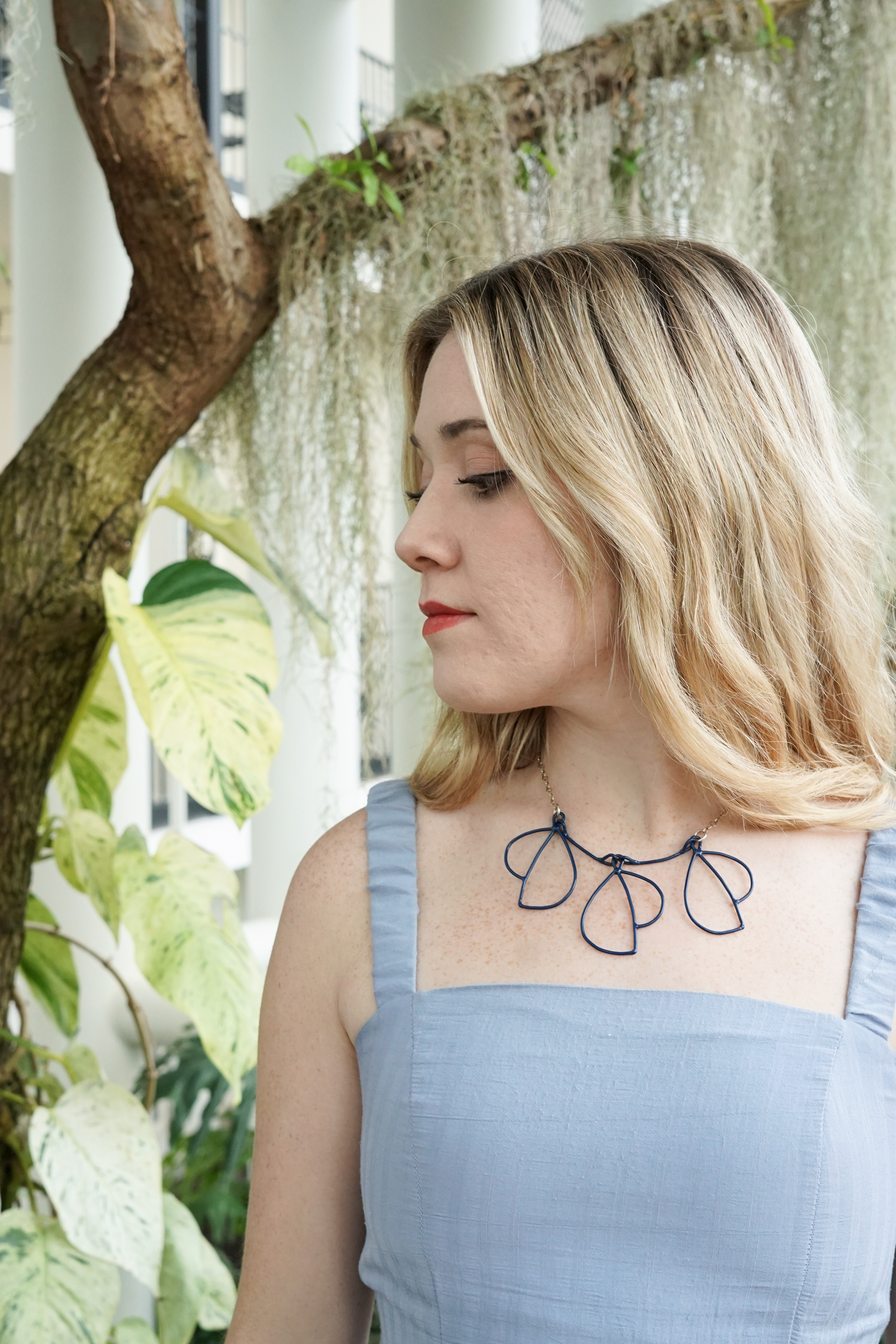 Trista in garden with blue dress and trivolo statement necklace