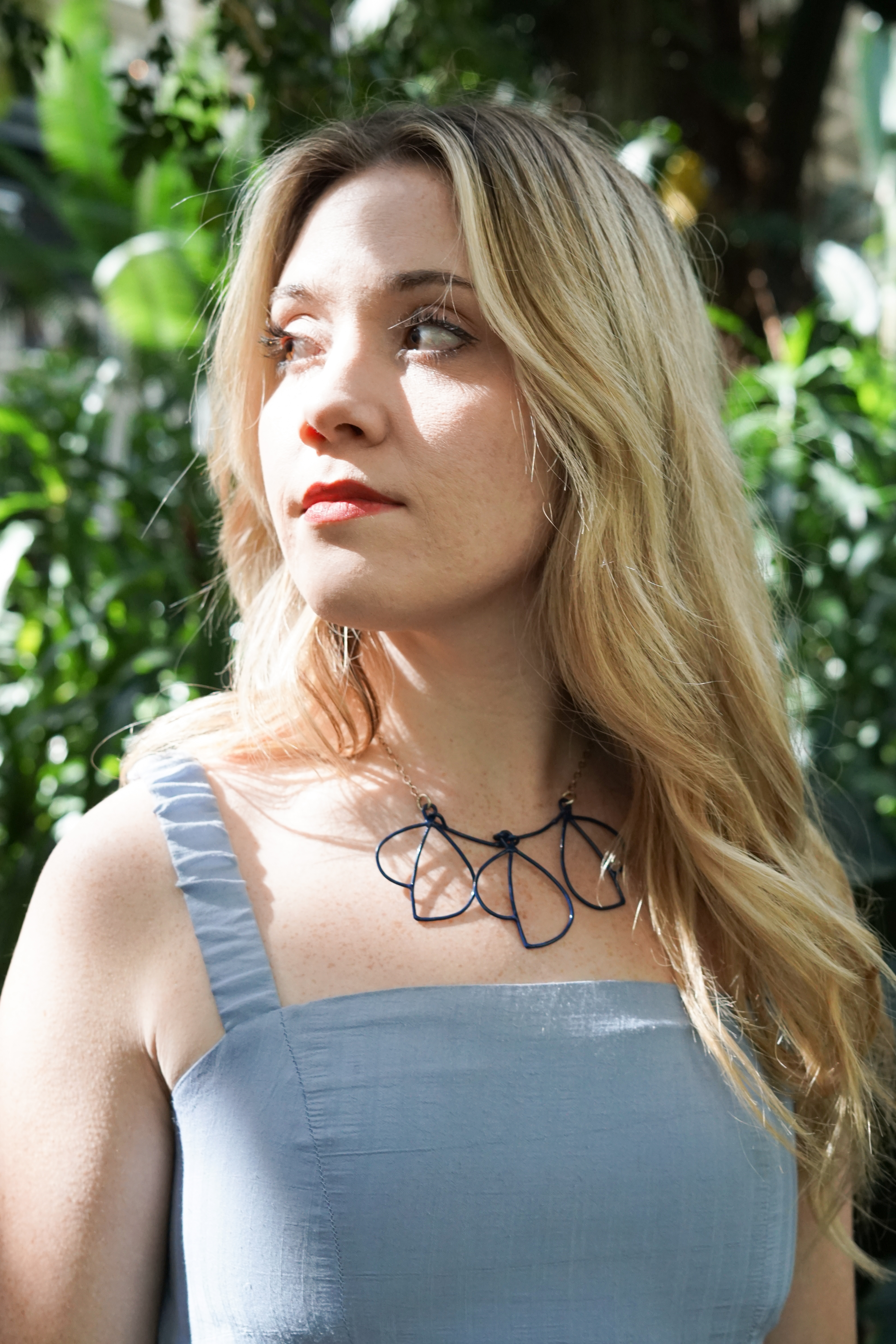 Trista in garden with blue dress and trivolo statement necklace