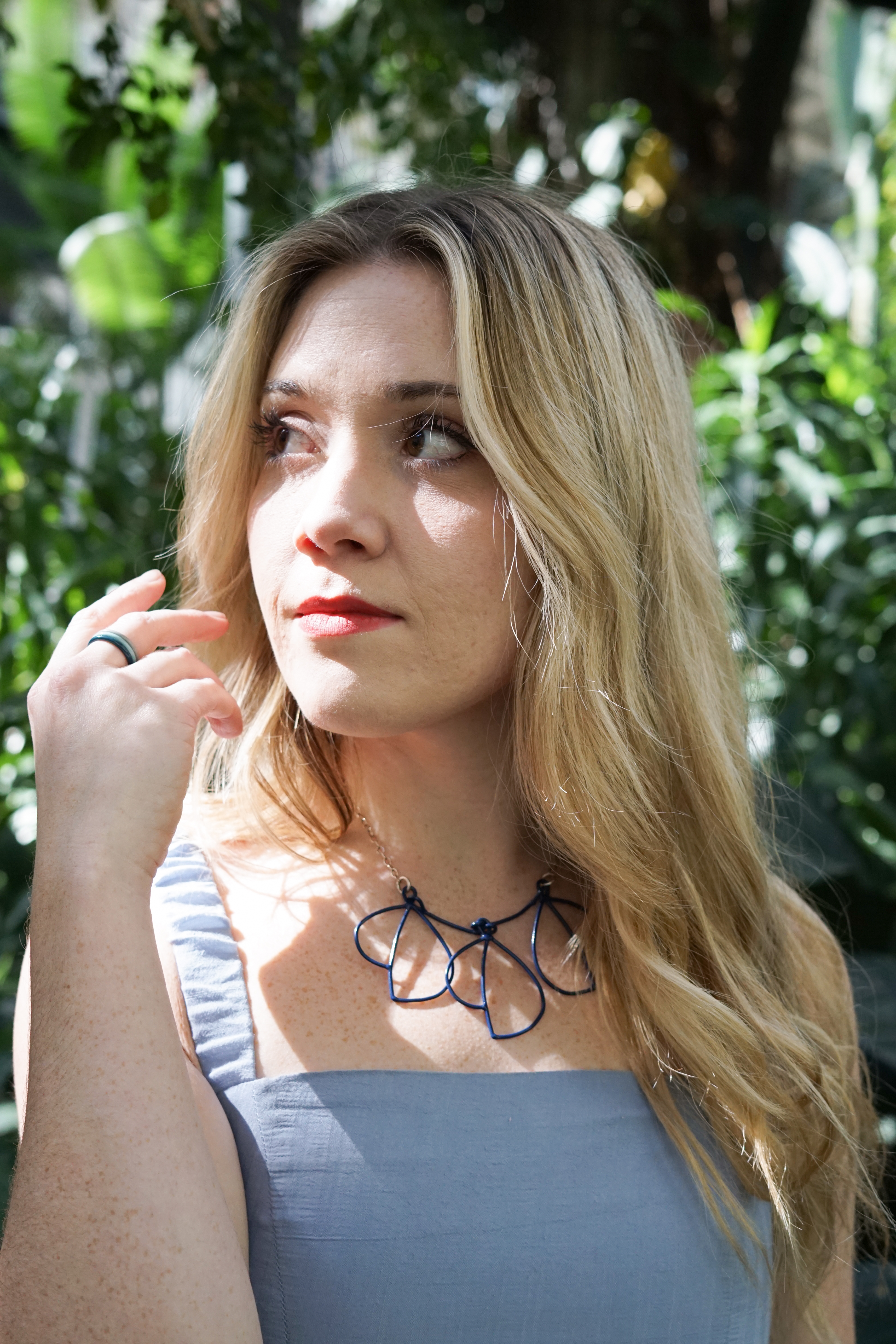Trista in garden with blue dress and trivolo statement necklace