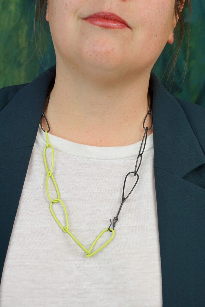 unique professional style:  neon necklace, white t-shirt, dark teal blazer