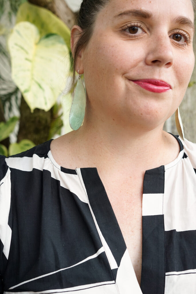 light green statement earrings, plants, and black and white dress