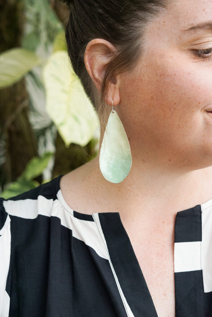 light green statement earrings, plants, and black and white dress