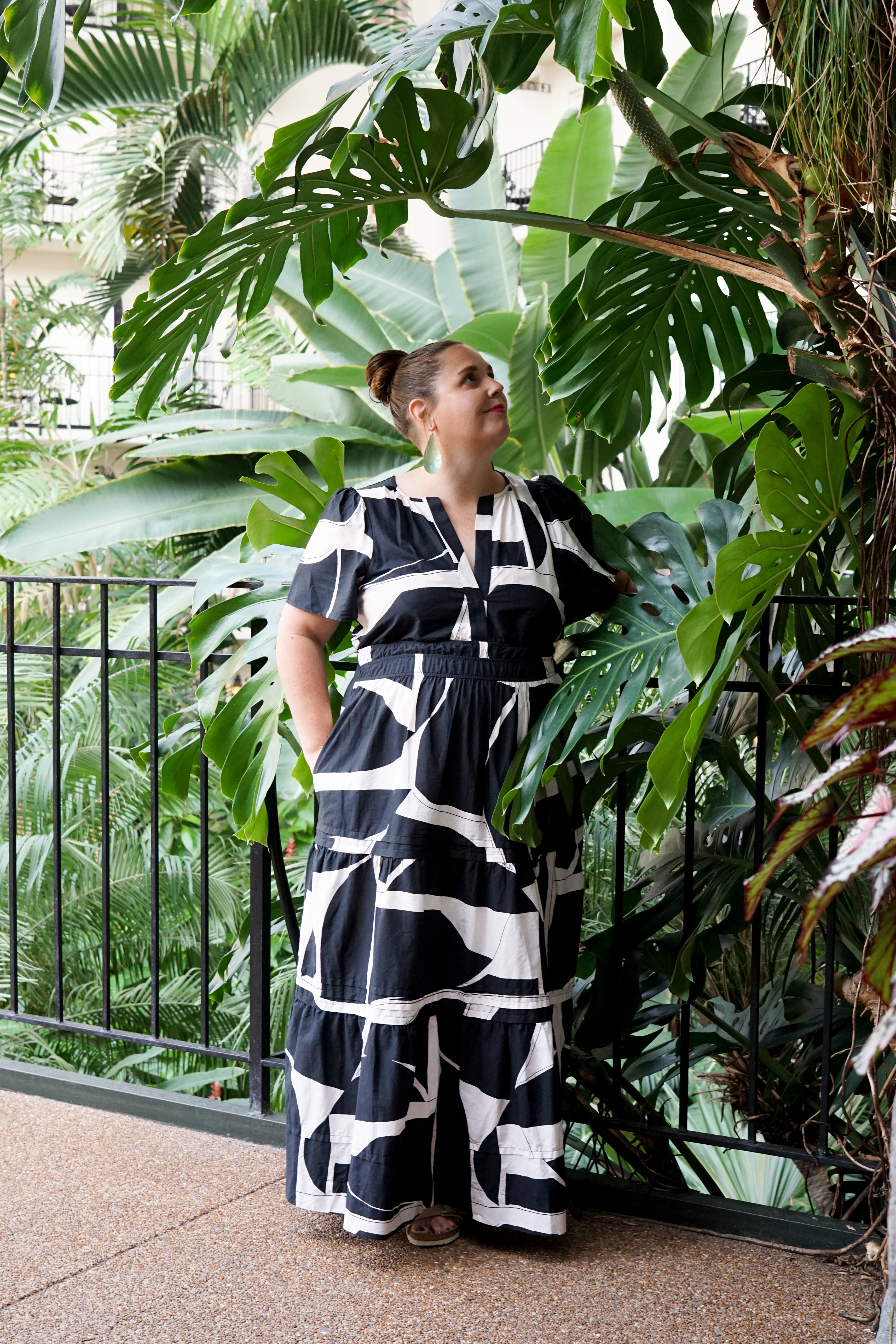 black and white dress with statement earrings in a botanical garden with large monstera plant