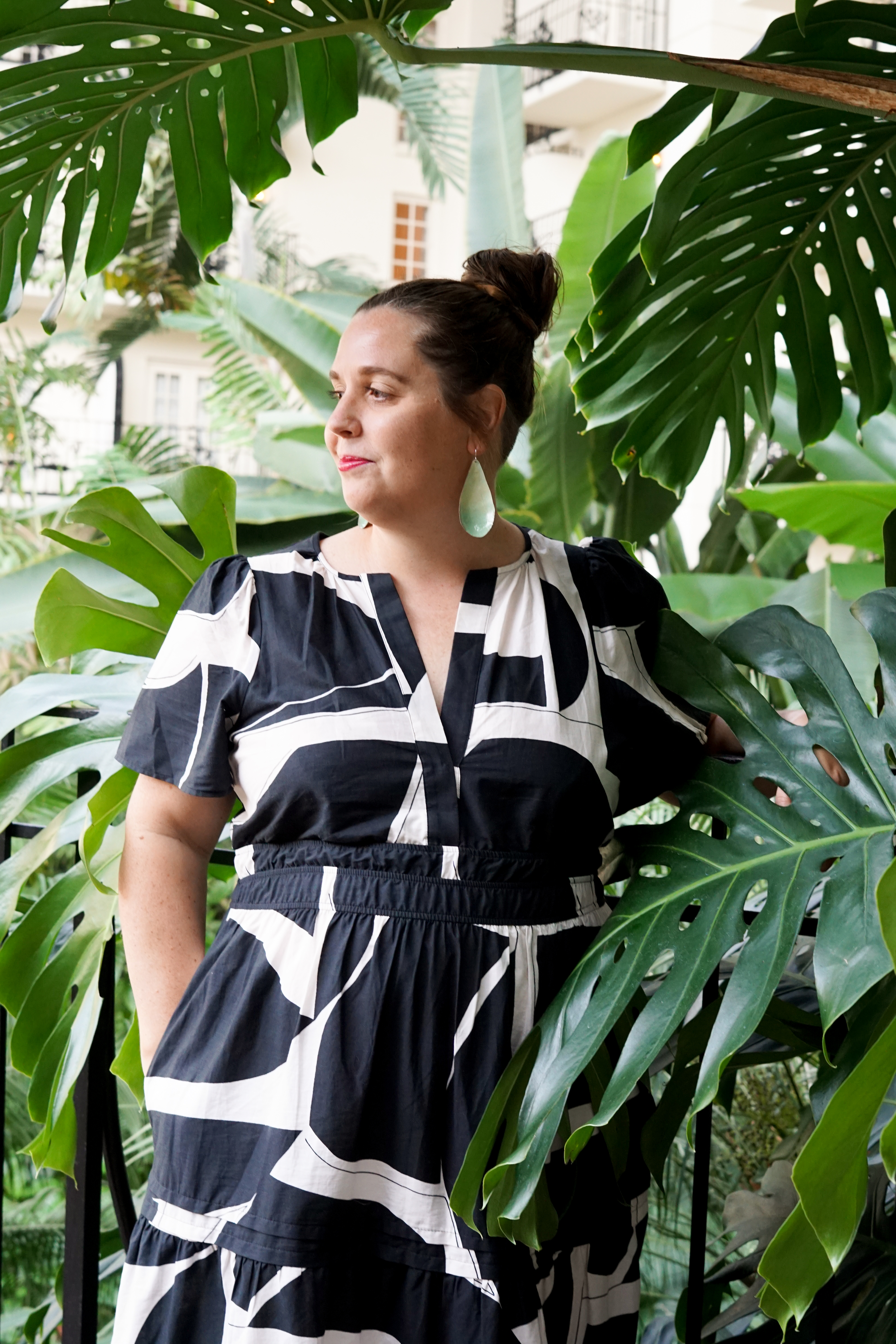 black and white dress with statement earrings in a botanical garden with large monstera plant