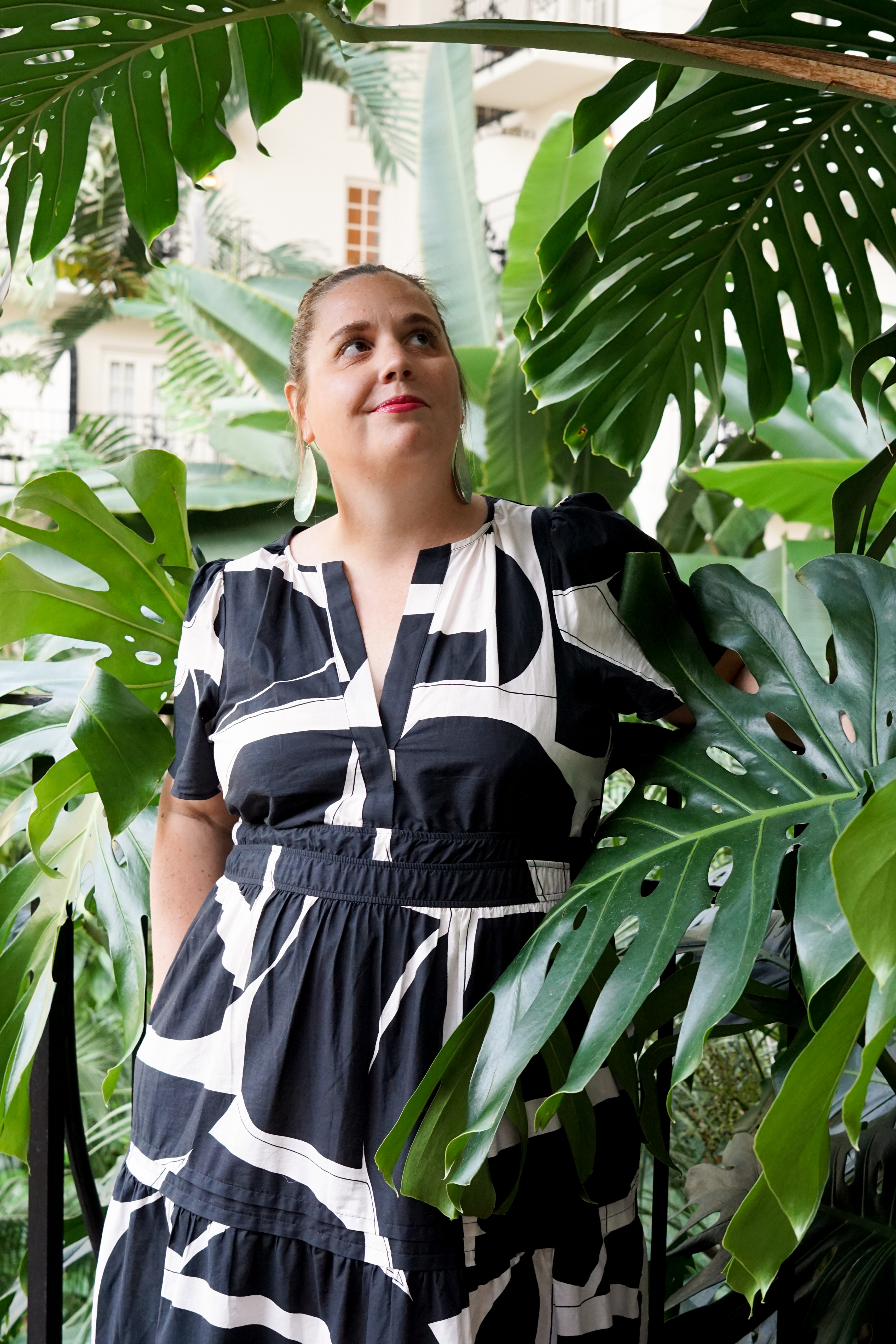 black and white dress with statement earrings in a botanical garden with large monstera plant