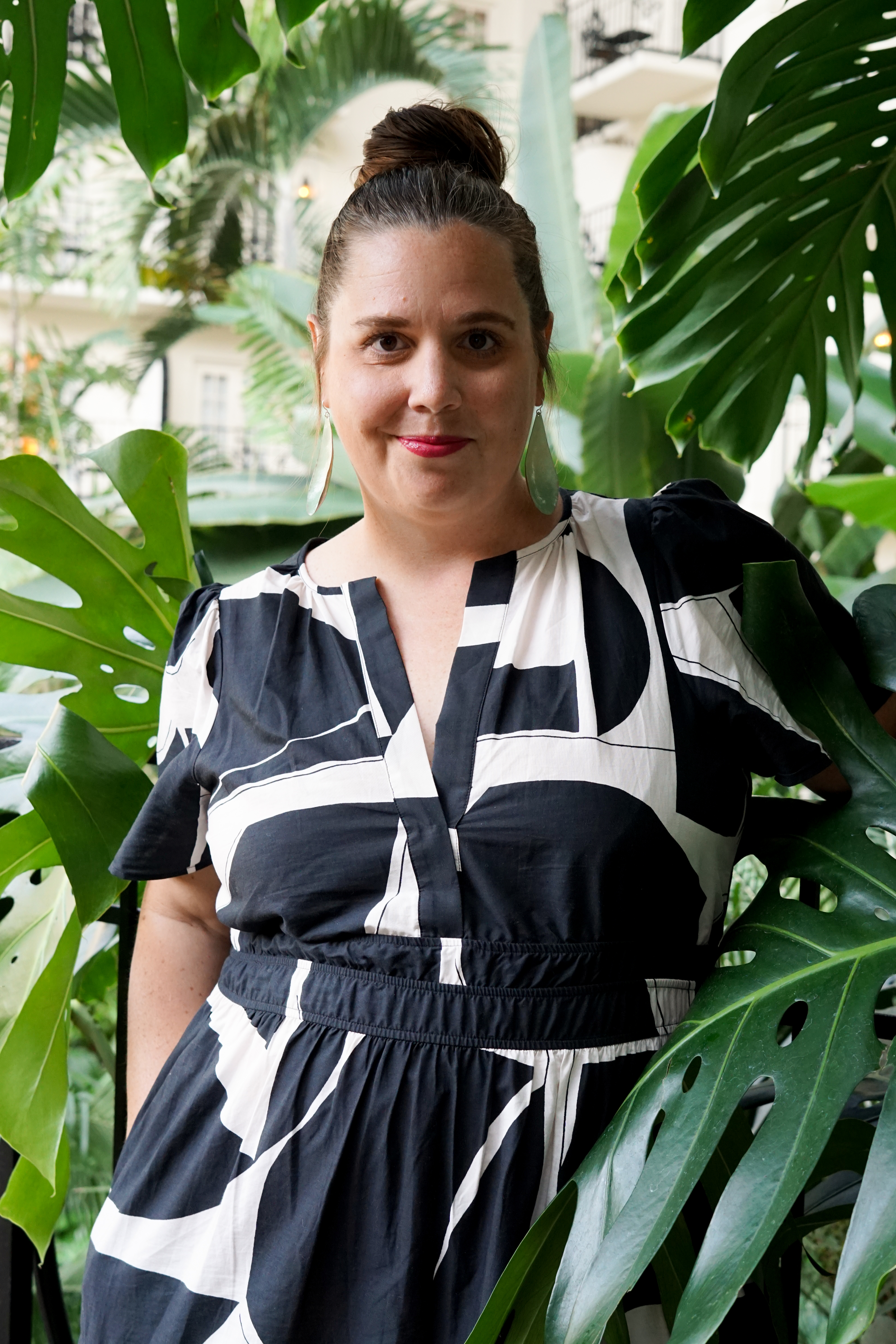 black and white dress with statement earrings in a botanical garden with large monstera plant