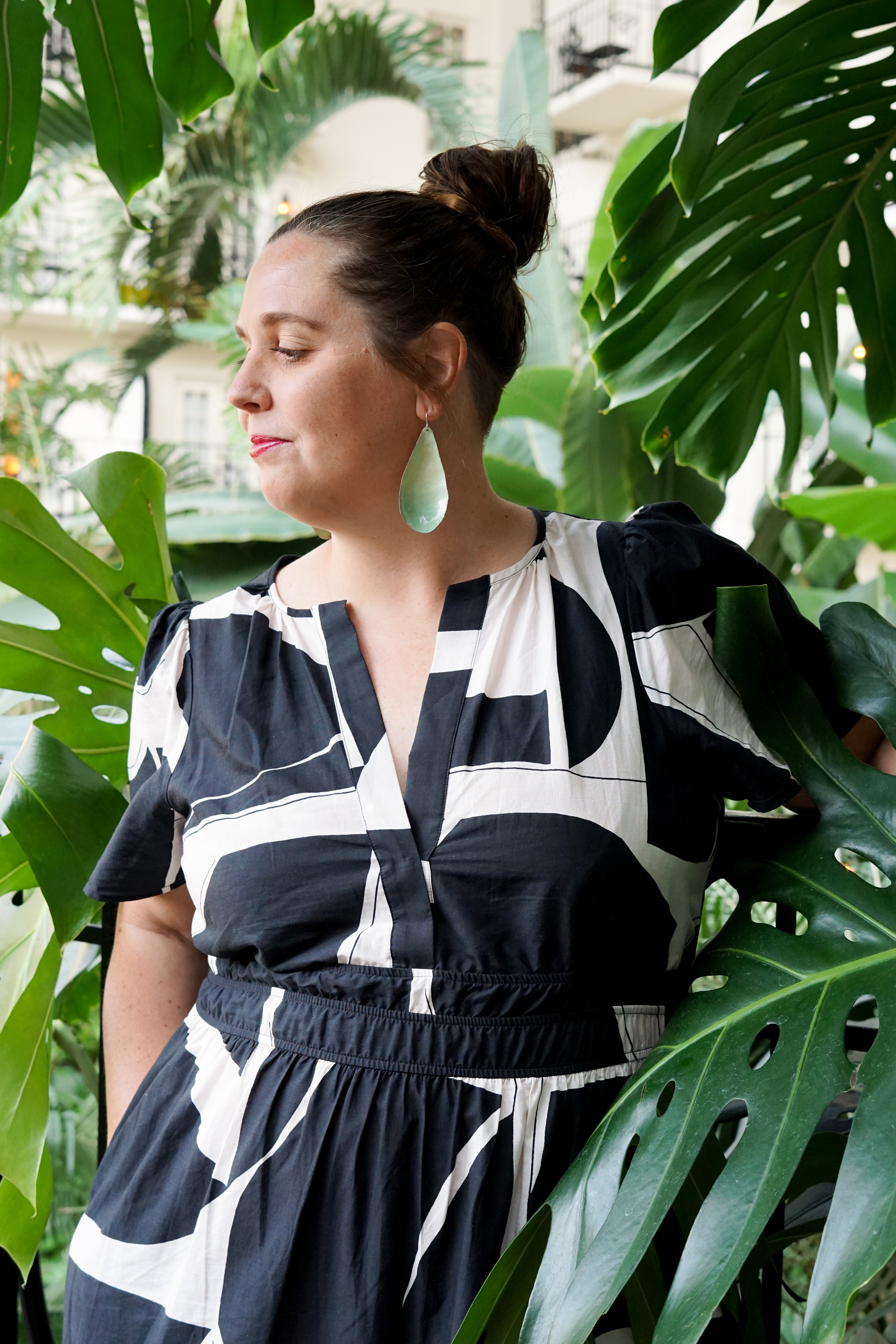 black and white dress with statement earrings in a botanical garden with large monstera plant