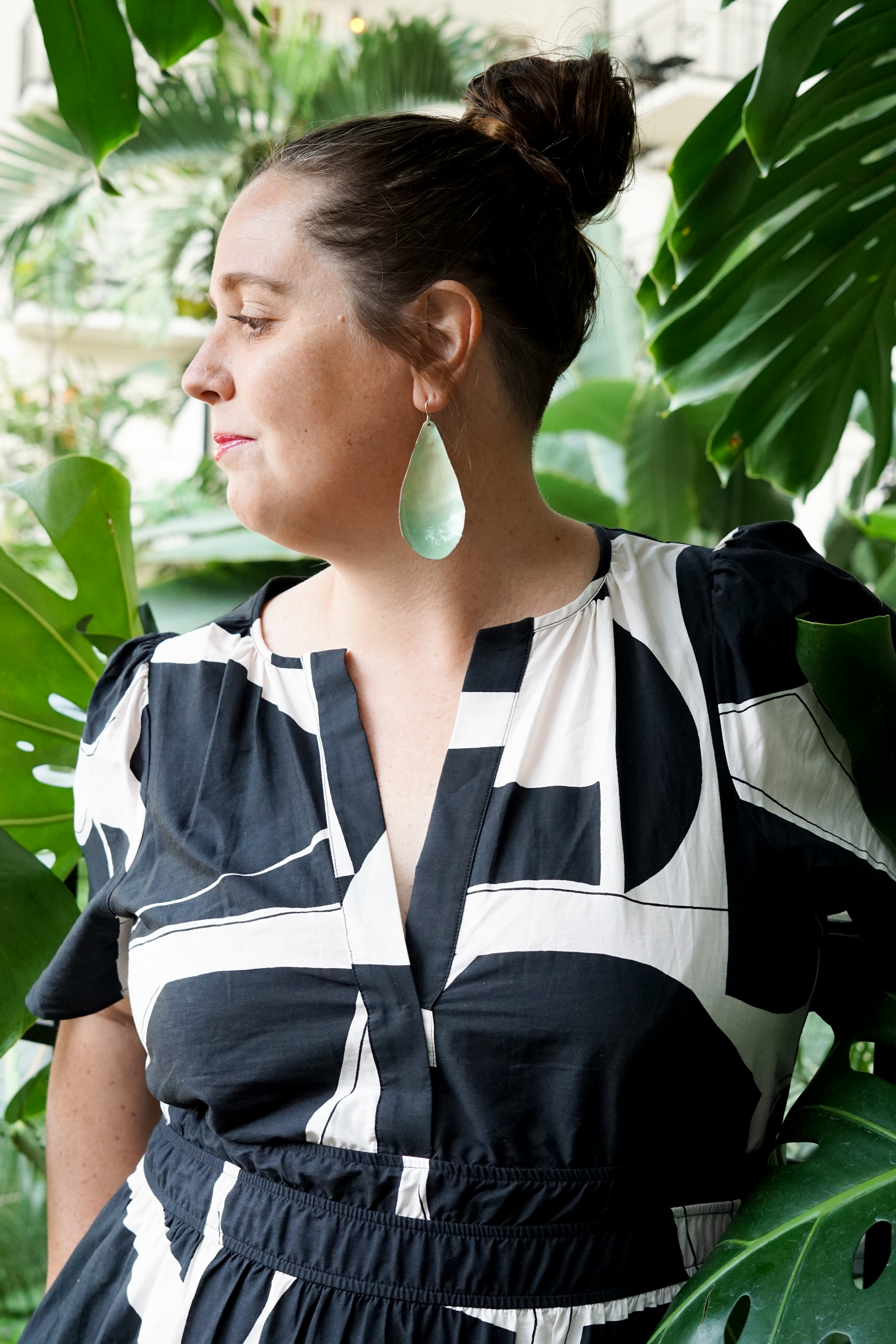 black and white dress with statement earrings in a botanical garden with large monstera plant