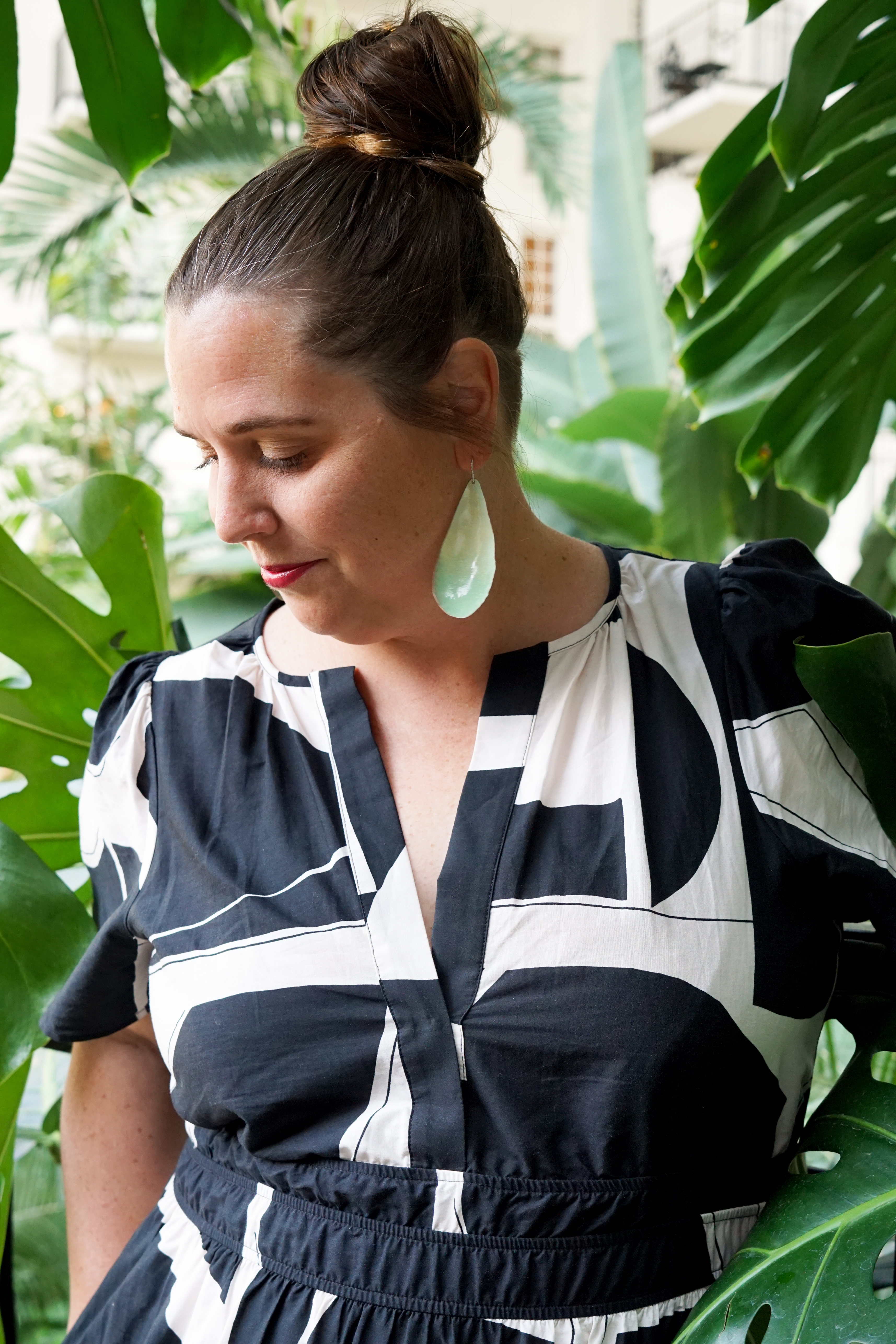 black and white dress with statement earrings in a botanical garden with large monstera plant