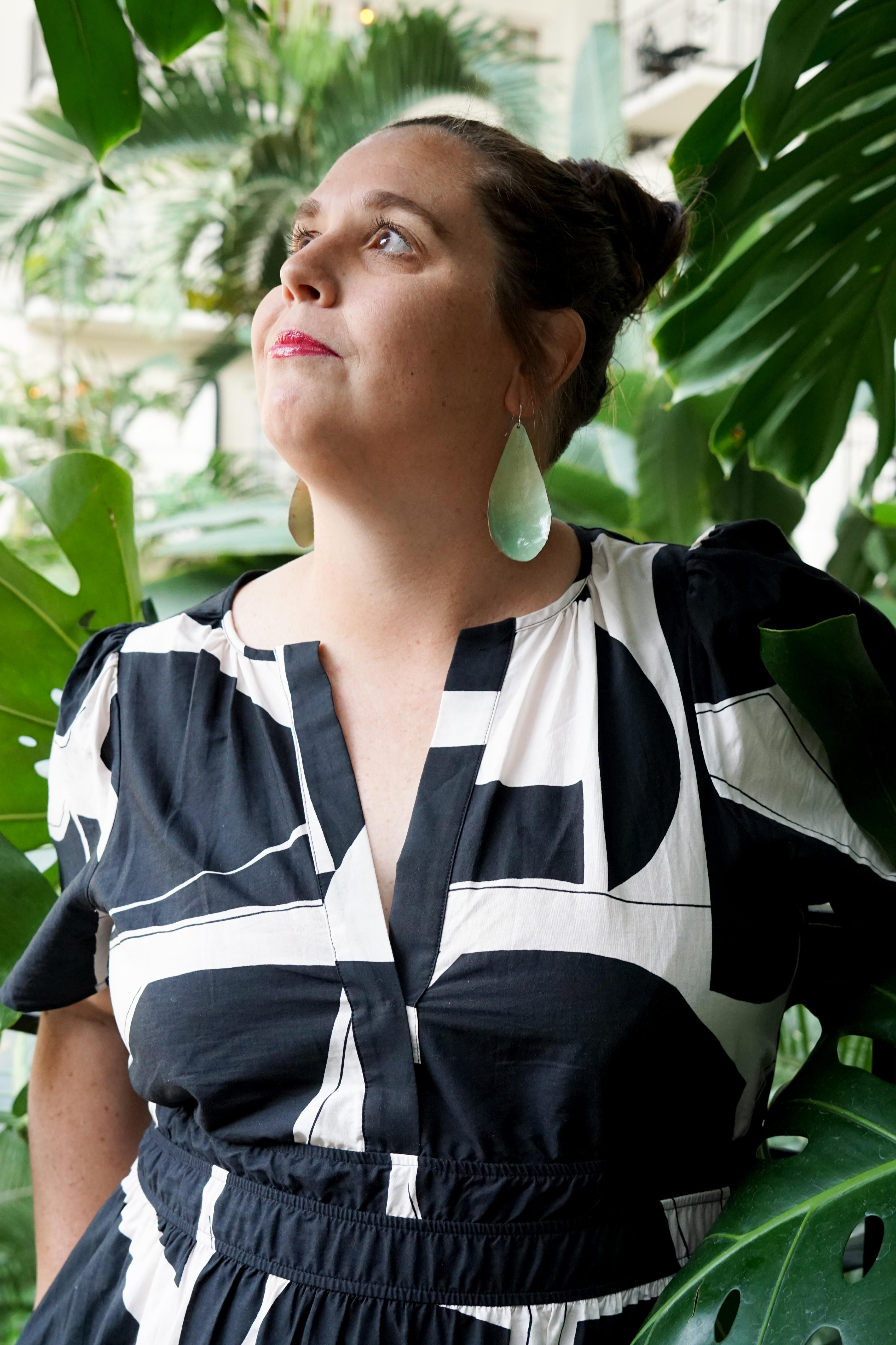 black and white dress with statement earrings in a botanical garden with large monstera plant