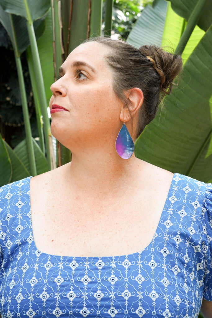 blue and purple statement earrings with blue dress in botanical garden