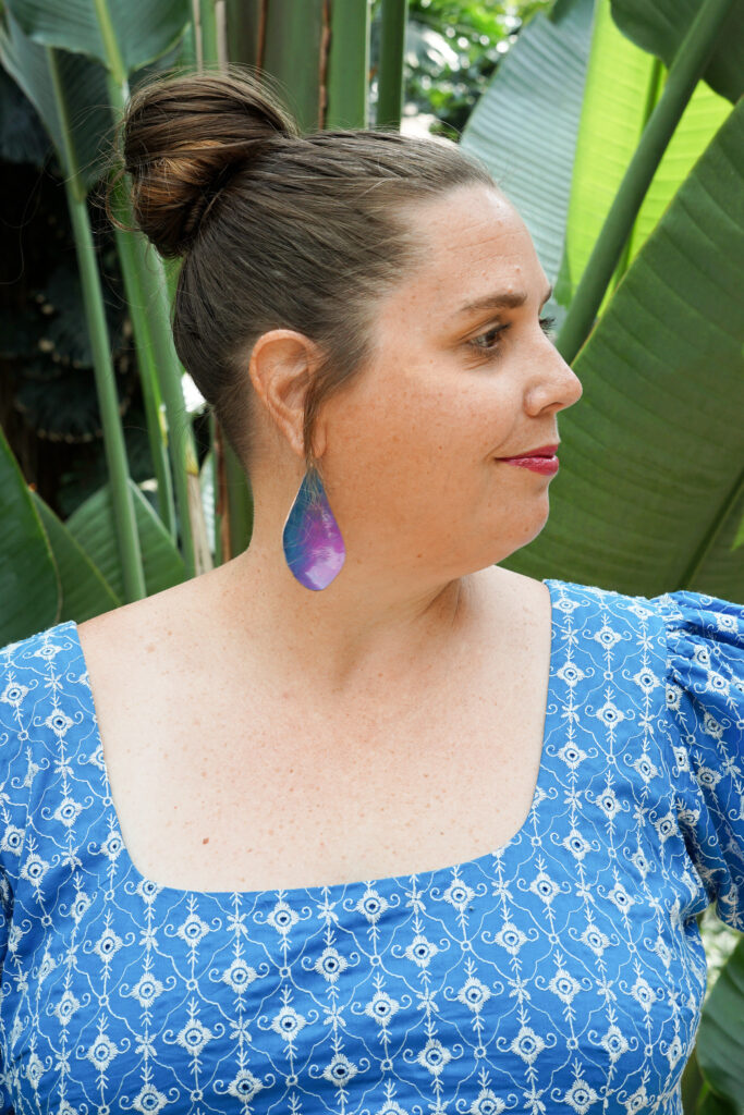 blue and purple statement earrings with blue dress in botanical garden