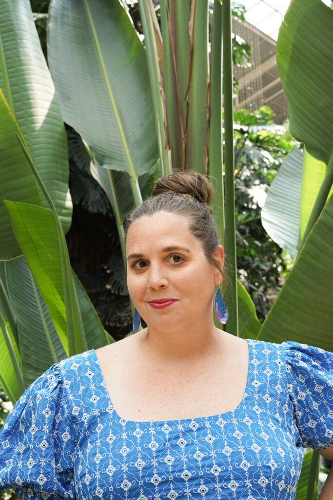 blue and purple statement earrings with blue dress in botanical garden