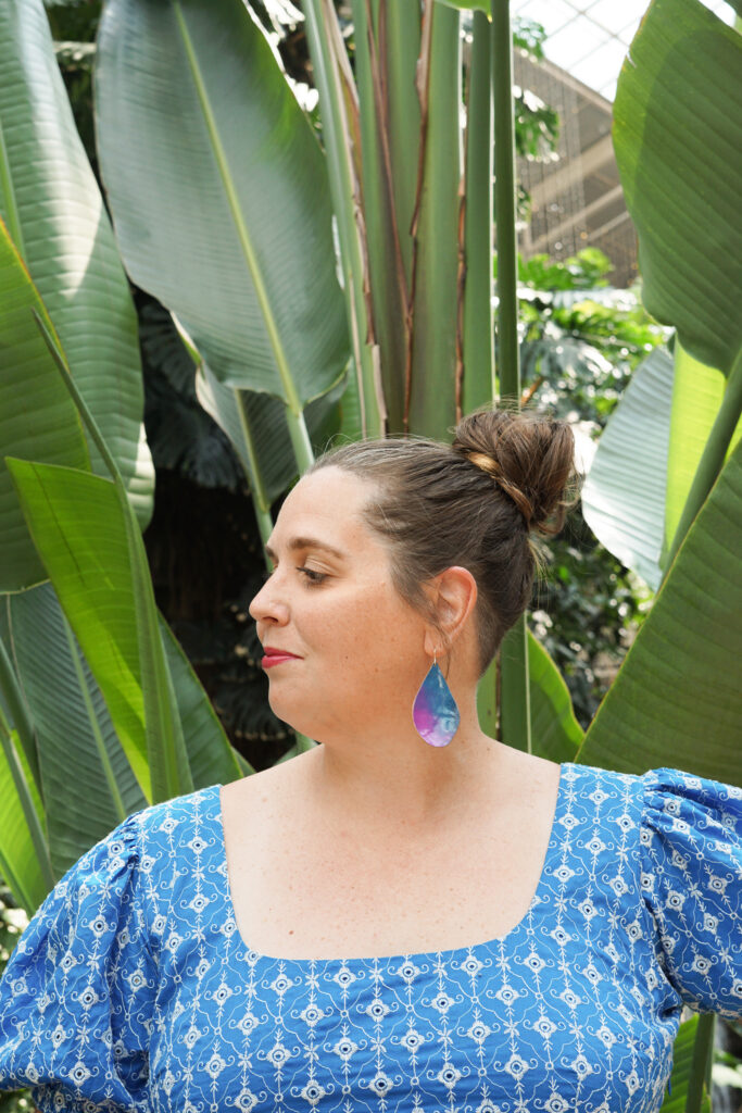 blue and purple statement earrings with blue dress in botanical garden