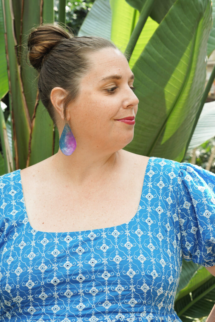 blue and purple statement earrings with blue dress in botanical garden