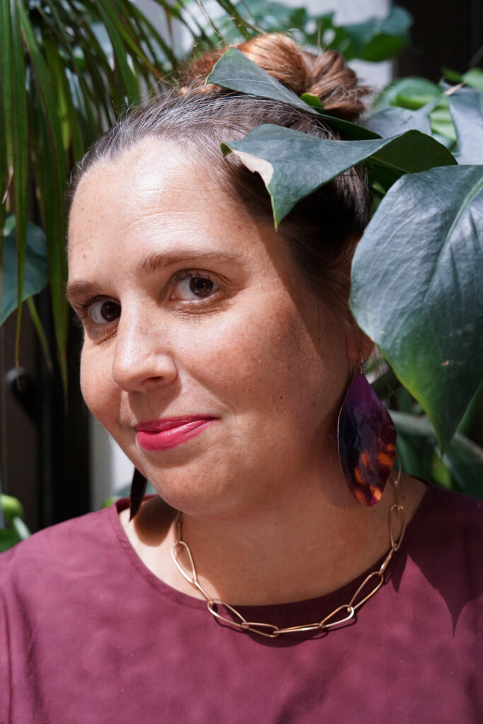 portrait with monstera - fall style jewelry and burgundy dress with bronze chain necklace