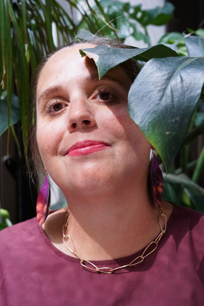 portrait with monstera - fall style jewelry and burgundy dress with bronze chain necklace